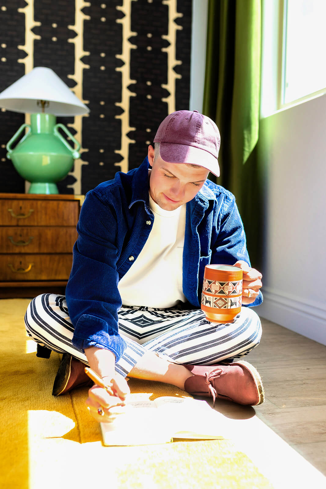 Arizona home buyer sitting on the floor reviewing notes with a coffee mug, representing the under contract stage of the home buying process.