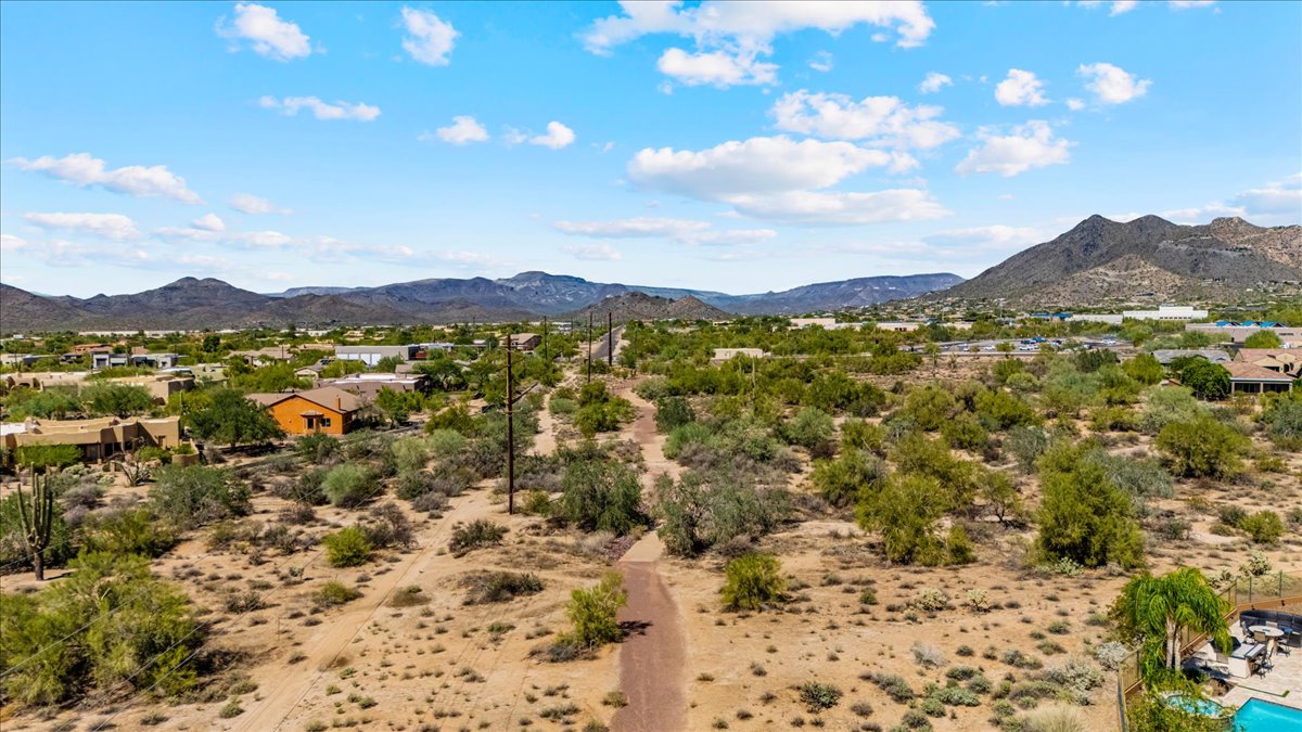 Aerial view of a desert trail in Cave Creek, Arizona with mountain views, natural open space, and surrounding homes, showing the landscape people enjoy when moving to Cave Creek.