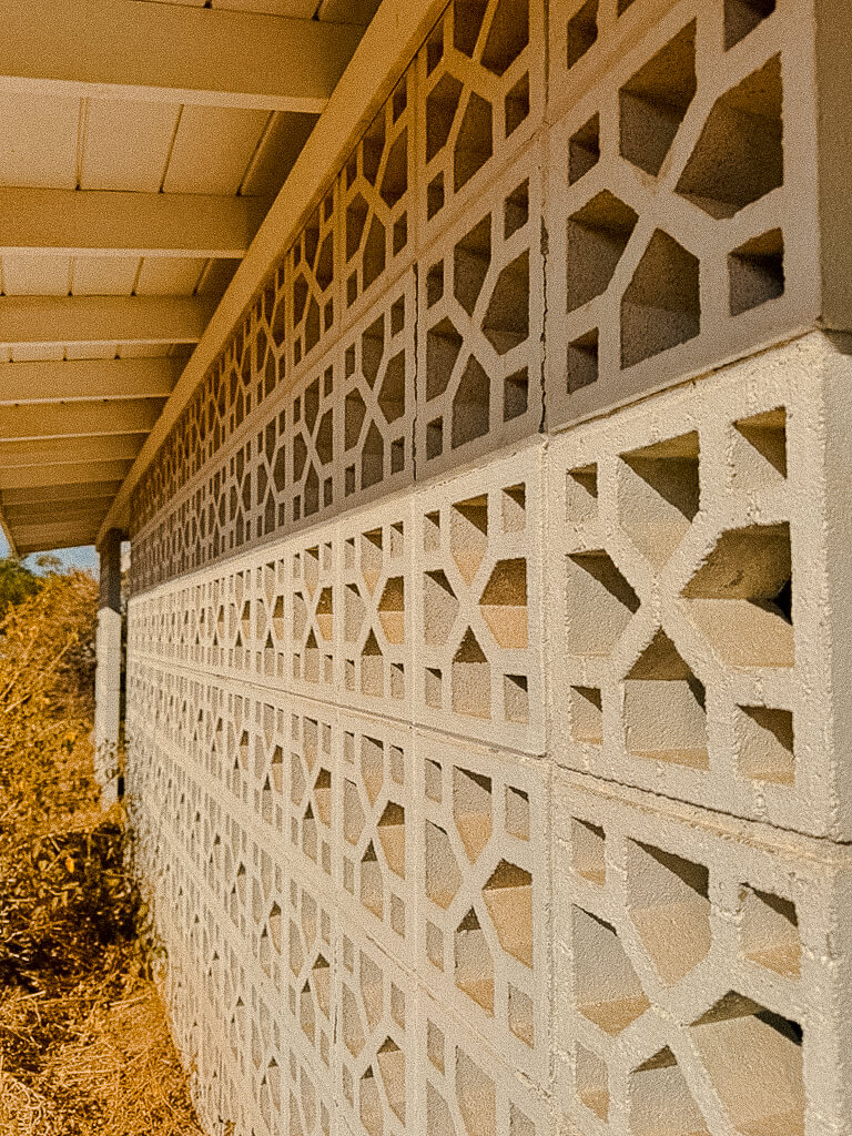 Geometric concrete breeze-block wall beneath an exposed-beam roof at an older Arizona home.